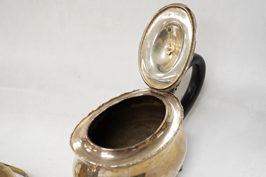A late Victorian silver oval teapot, William Hutton & Sons, London, 1899, together with a George III silver cream jug, London, 1811, gross weight 15.4oz.